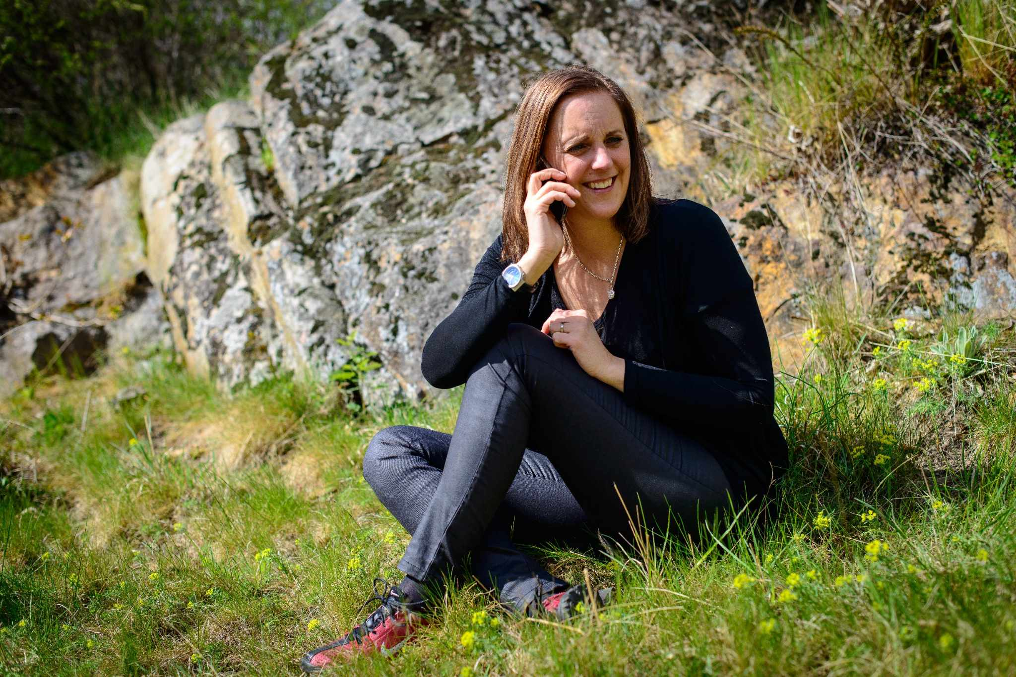 Bildbank för företag, kvinna sittande på klippa i naturmiljö med grönska i bakgrunden, exempel ur Sogetis bildmaterial